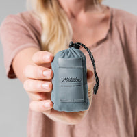 Woman holding slate blue Pocket Blanket Mini to camera