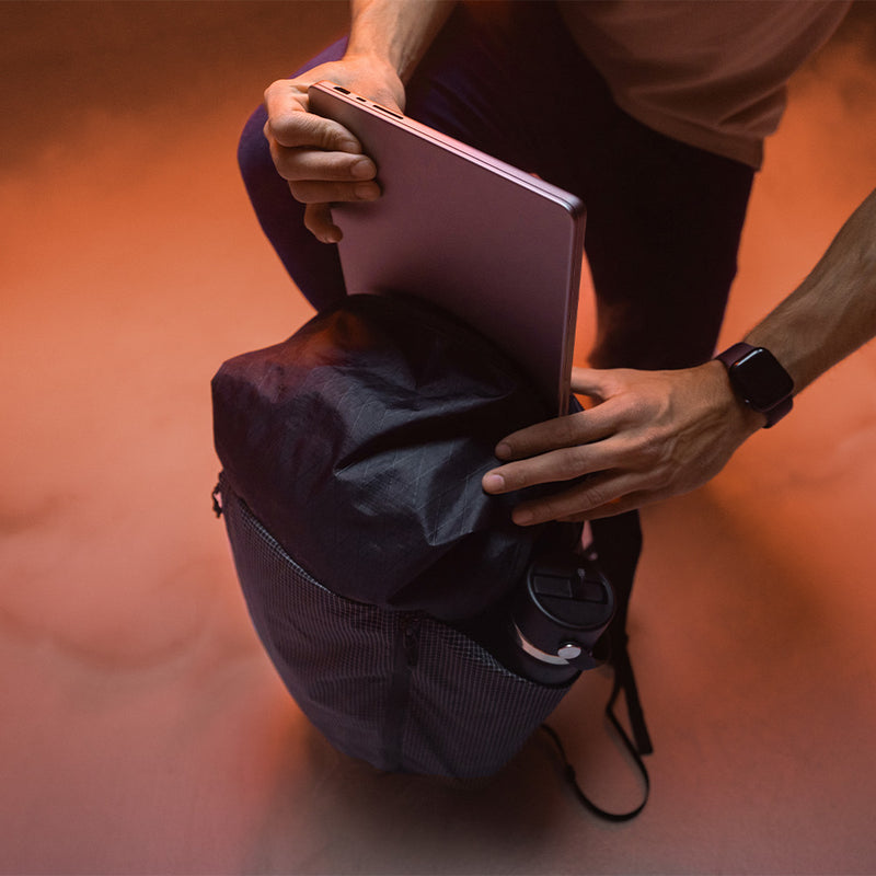 man in smoky, orange lit studio, placing laptop into edx backpack