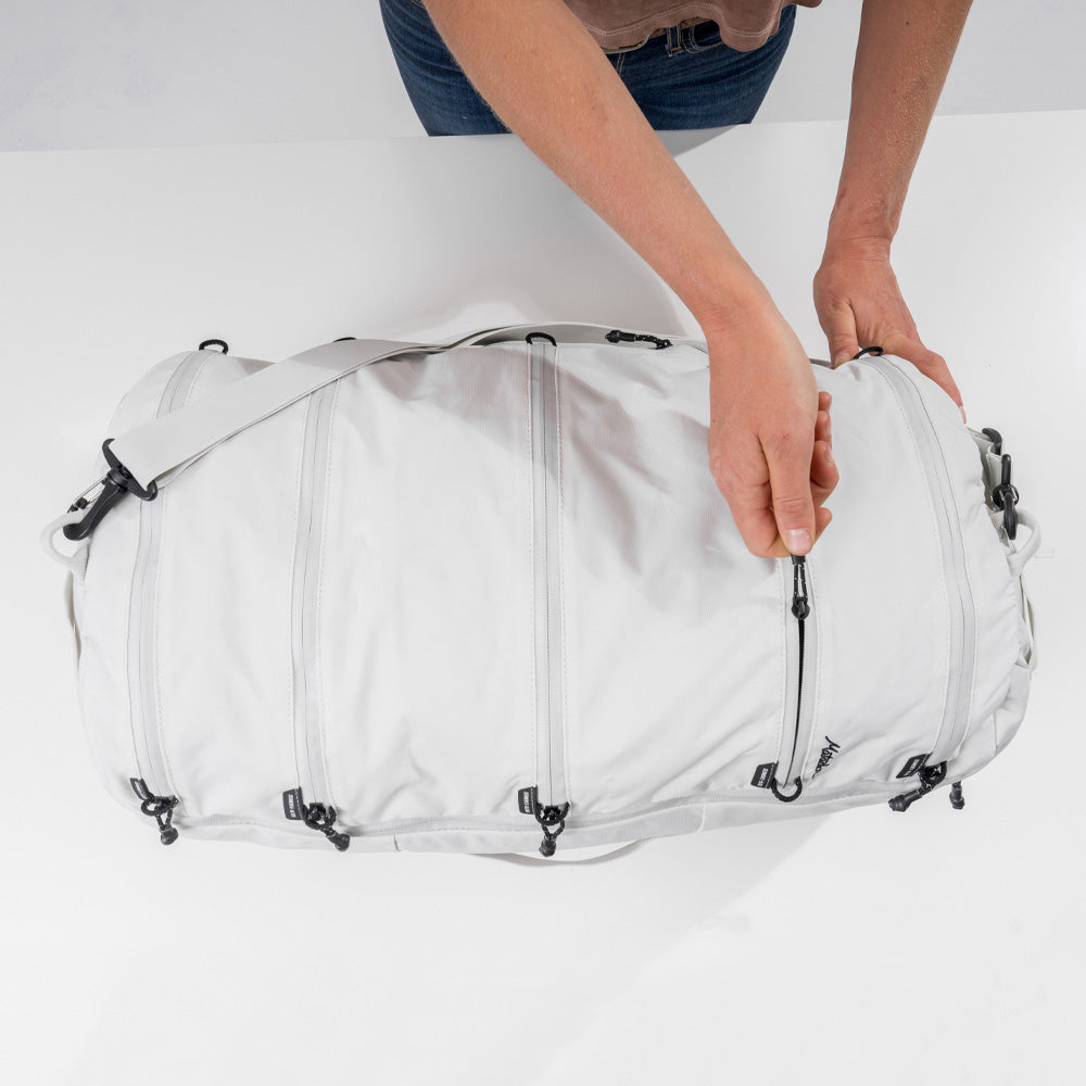 Woman with White SEG45 on white table, unzipping one of the segmented compartments