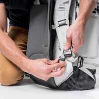 man connecting white Globerider45 shoulder straps to prep for storage