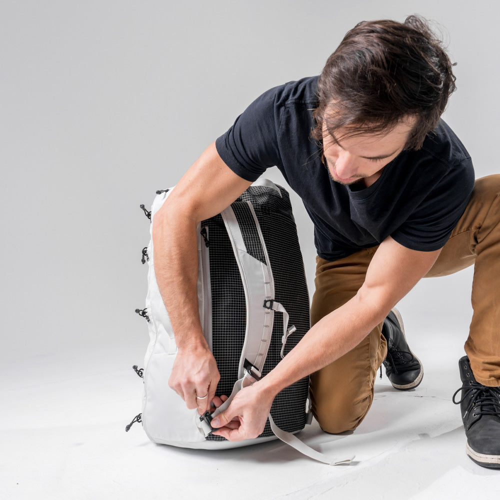 Man kneeling on white floor, detaching White SEG45 shoulder straps