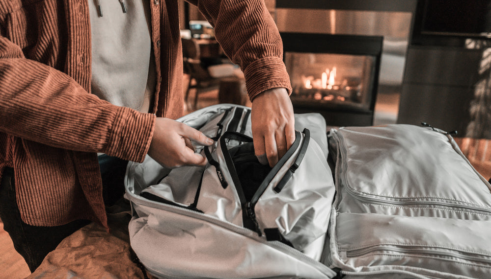 woman pulling clothing out of white gear cube, sitting in front of cozy fire place