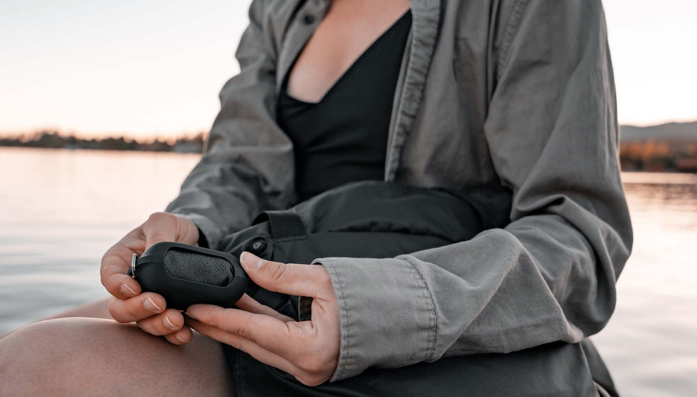 Woman sitting by lake, holding Trek Towel silicone case