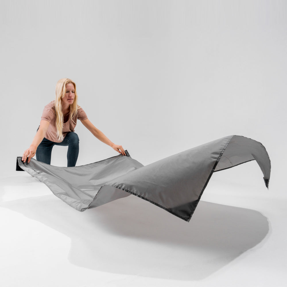 Blond woman in white studio setting, laying out Pocket Blanket