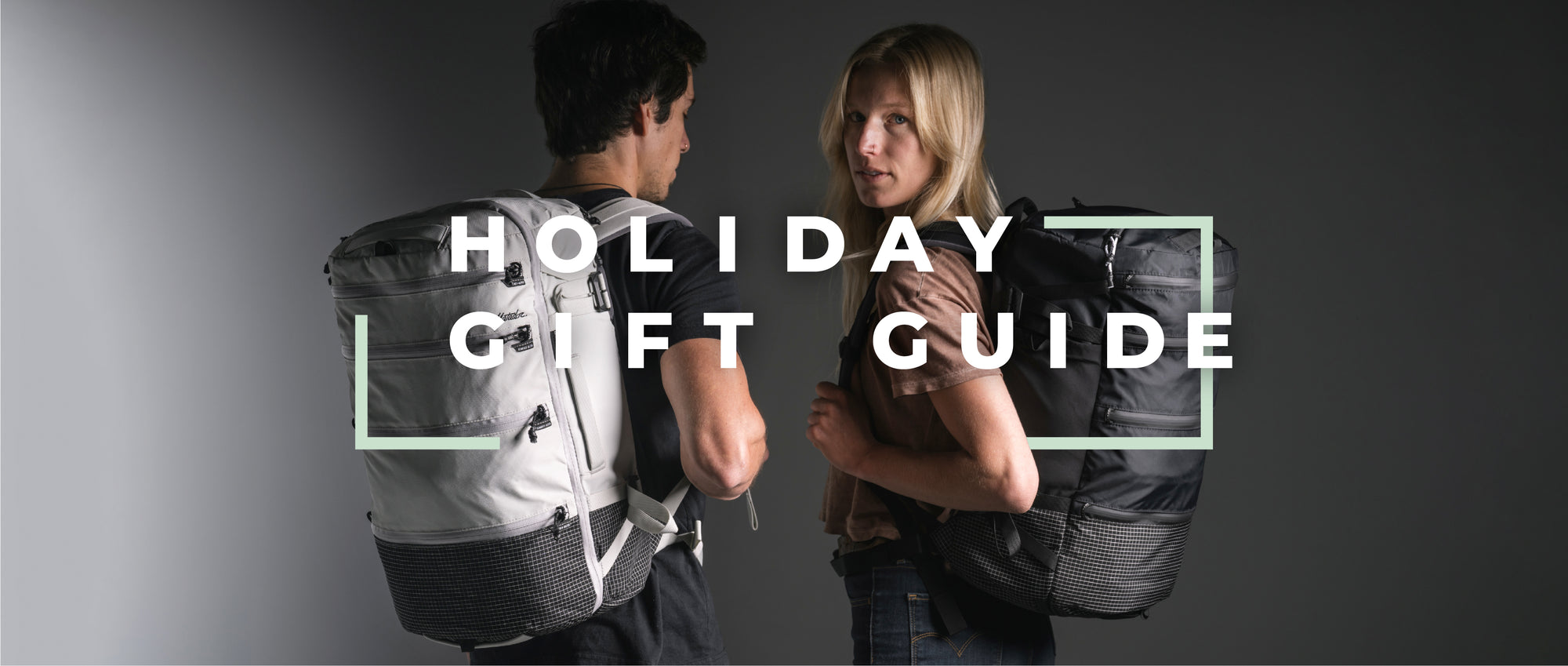 man and woman wearing black and white backpacks on dark gray background with text "holiday gift guide"