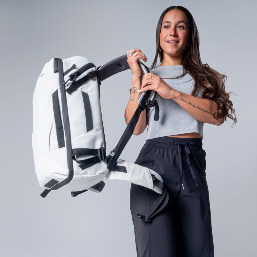 Woman on light gray background, swinging a white globerider35 over her shoulder