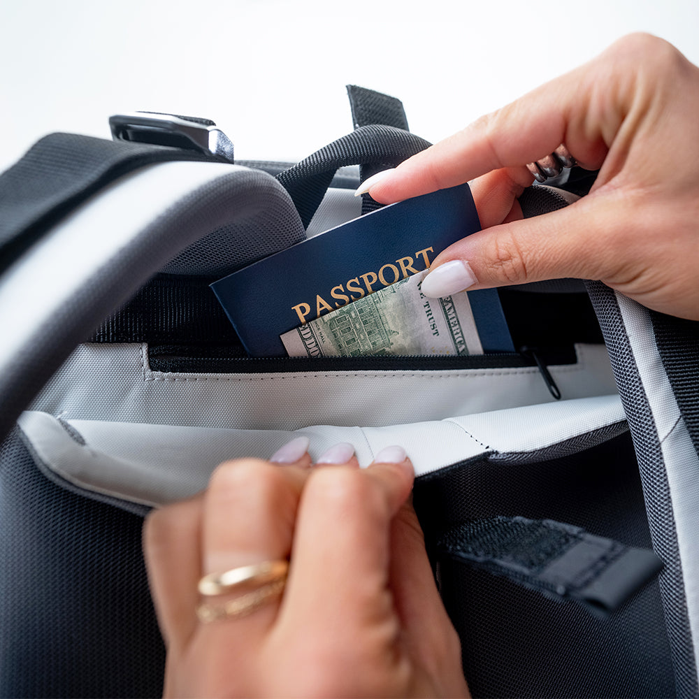 Close up view of woman's hands pulling passport out of hidden back panel pocket of white globerider35