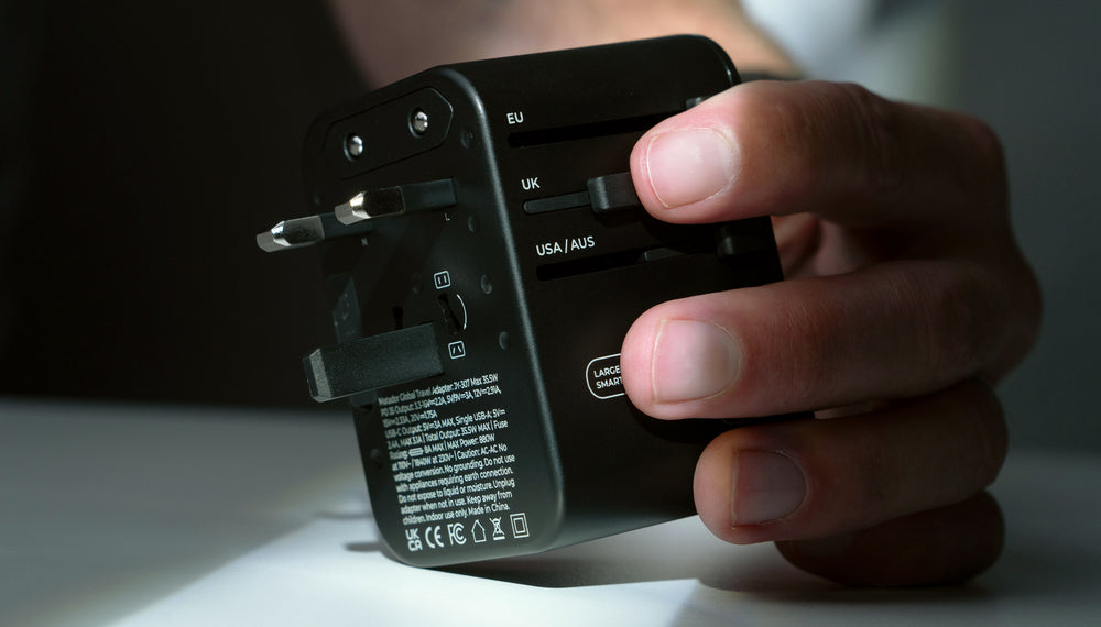 Close up view of back of Travel Adapter. Hand is pushing the UK slider to reveal UK outlet prongs