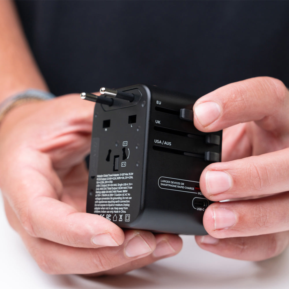 close up view of hands holding travel adapter, pushing EU prong slider out