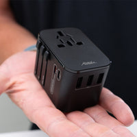 black travel adapter sitting in the palm of a man's hand