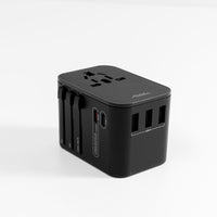 black travel adapter laying on its back on white background