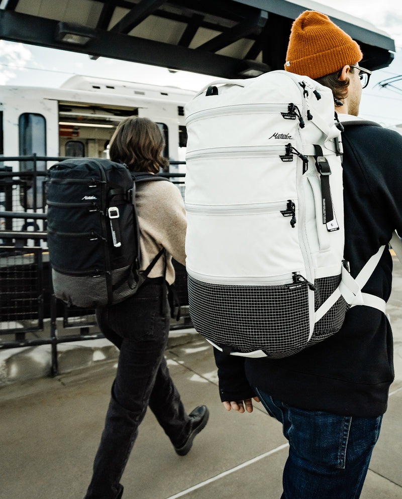 man an woman walking on train platform wearing black and white seg28 backpacks