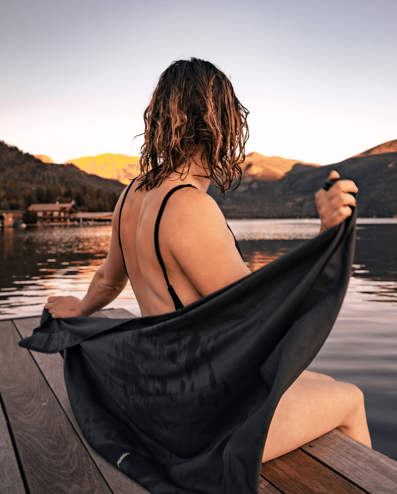 woman on lake dock at sunset, wrapping herself in charcoal nanodry towel