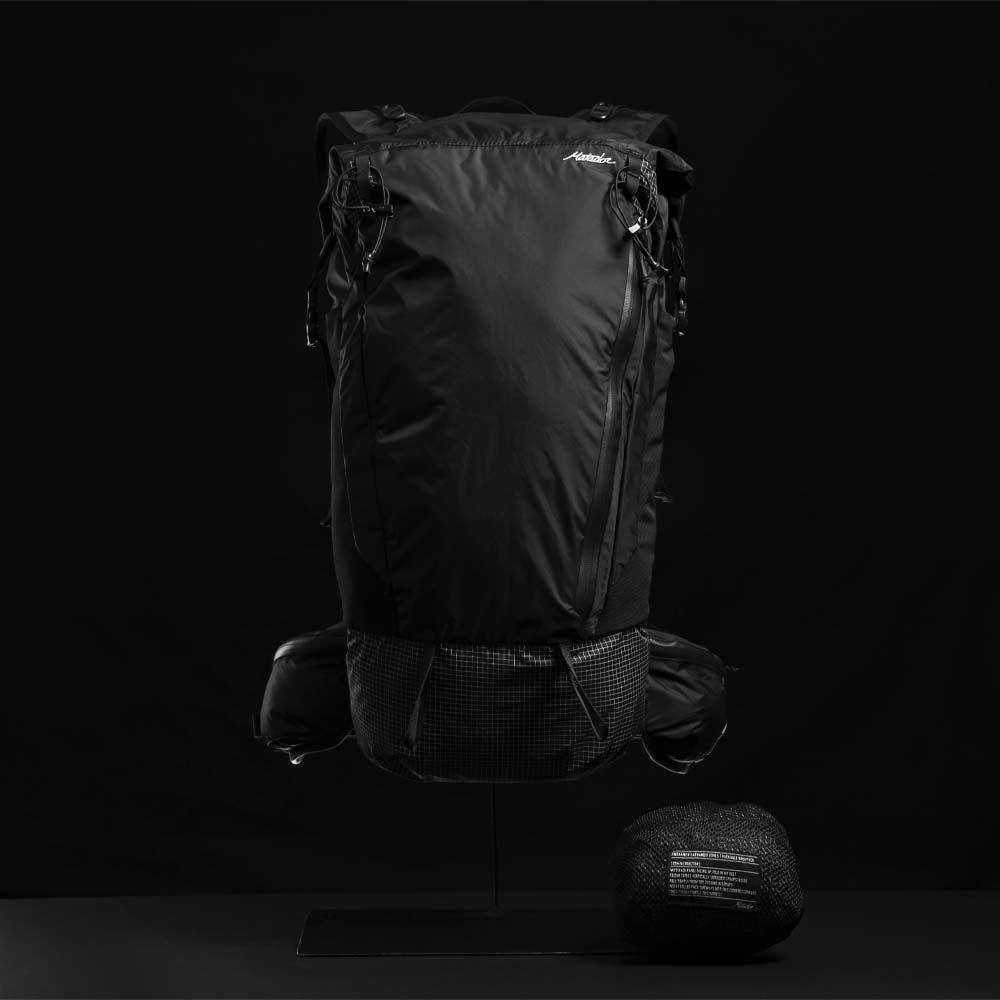 Front view of backpack and packed down pouch on black background