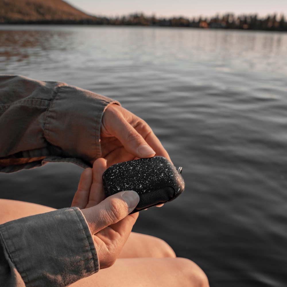 Woman sitting at lake, holding the Black Granite NanoDry Trek Towel silicone case