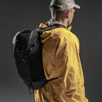 3/4 view of man wearing backpack on black background