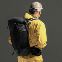 3/4 view of man wearing backpack on black background