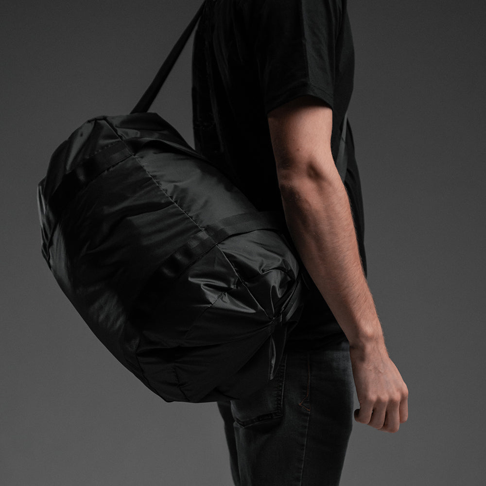 Man with duffle cross-strapped over his shoulder on black background