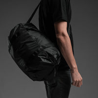 Man with duffle cross-strapped over his shoulder on black background